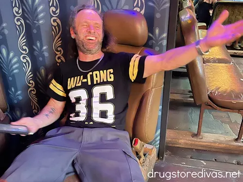 A man in a chair wearing a Wu Tang shirt.