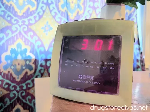 A white and purple alarm clock on a side table.