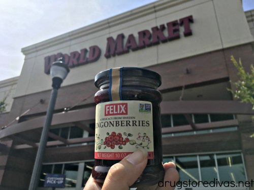 A hand holding a jar of lingonberry jelly in front of World Market.
