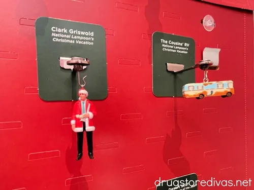 Two National Lampoon Christmas Vacation-themed Christmas ornaments hanging in a display.