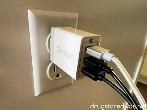 A phone charger with three wires plugged into an outlet.
