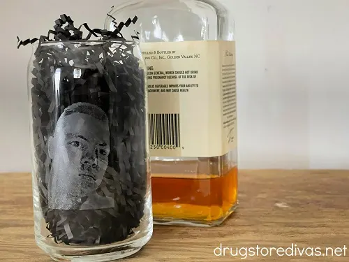 Engraved mug next to a bottle of liquor.