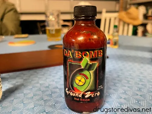 A bottle of Da Bomb Hot Sauce on a table with a blue tablecloth.