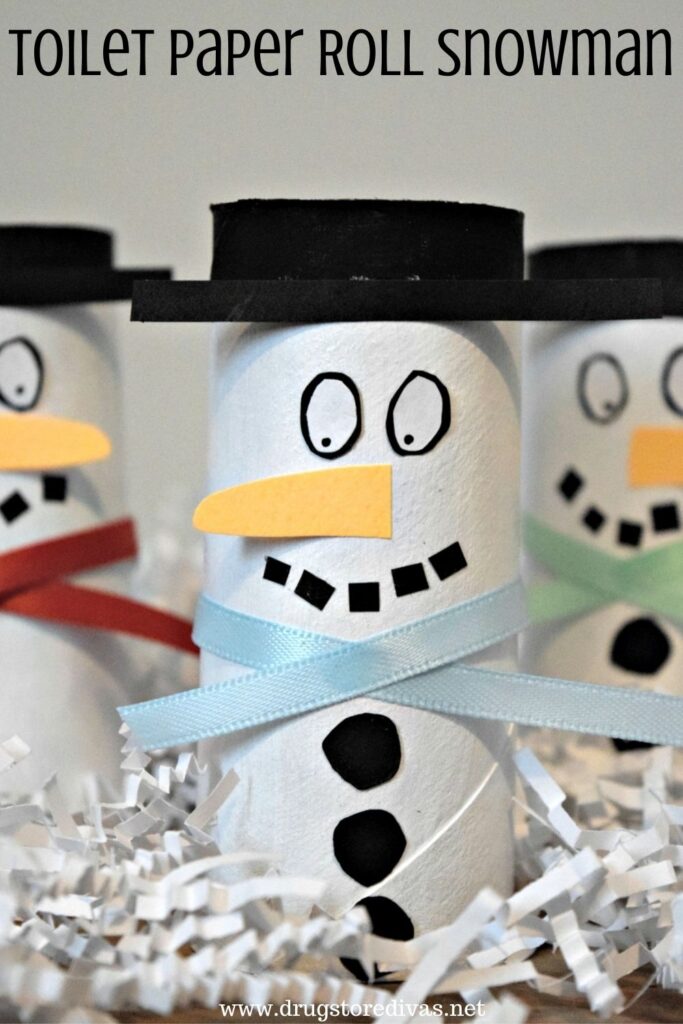 Three snowmen made from cardboard tubes in white paper shred with the words "Toilet Paper Roll Snowman" digitally written on top.