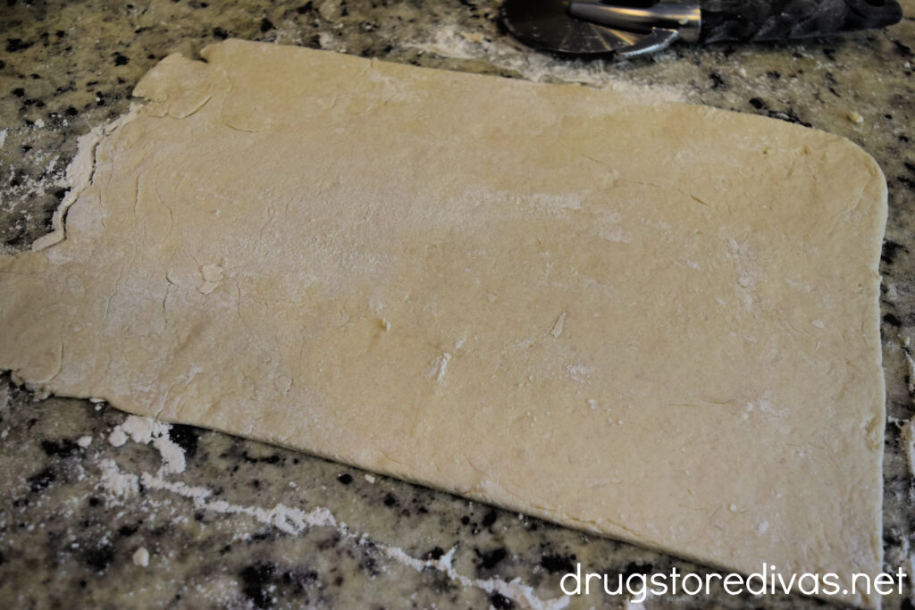 Cinnamon roll dough in a rectangle on a countertop.