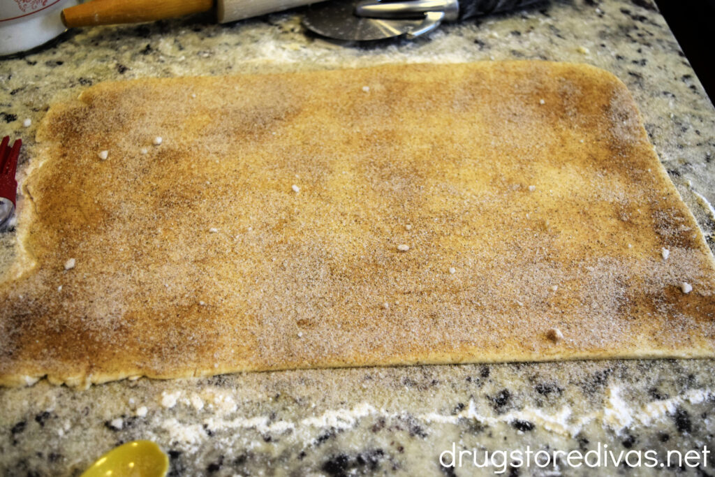 Cinnamon and sugar spread on a rectangular piece of dough on a counter.
