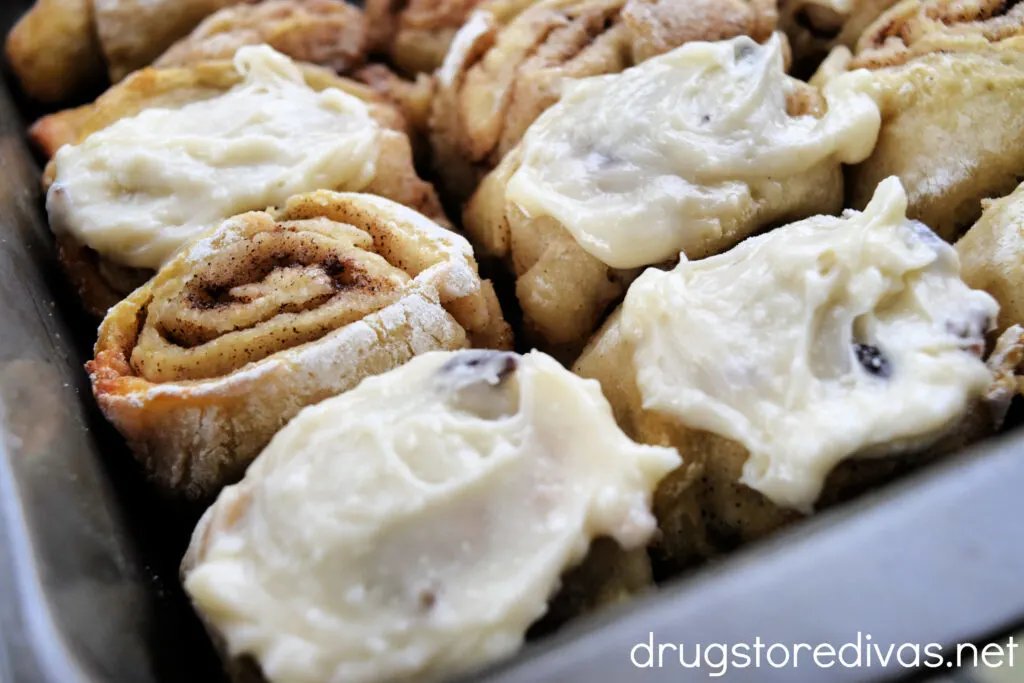 Cinnamon rolls, some with icing, in a pan.
