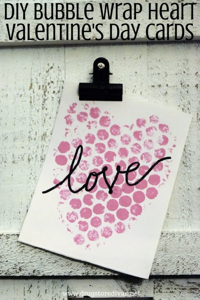 A homemade card on a clipboard with the words "DIY Bubble Wrap Heart Valentine's Day Cards" digitally written on top.