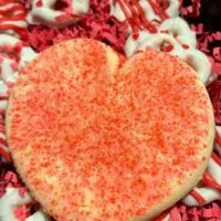 A heart-shaped sugar cookie and Valentine's Day pretzels in a box with the words 