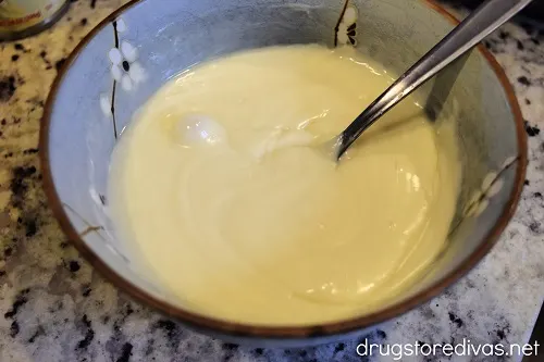 Melted white chocolate in a bowl with a spoon.