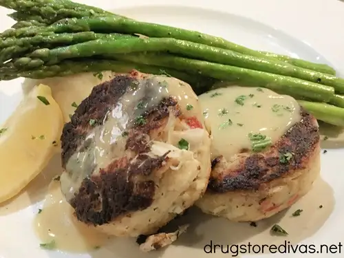 Two crab cakes, asparagus, and lemon on a white plate from Cape Fear Seafood Company in Leland, NC.