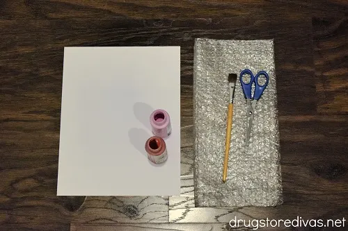 Cardstock, pink and red paint, a paint brush, scissors, and bubble wrap.