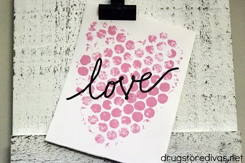 A DIY Bubble Wrap Heart Valentine's Day Cards hanging on a clipboard.