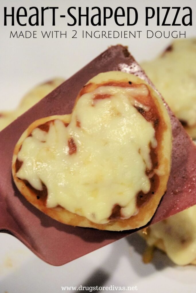 A heart-shaped pizza on a spatula with the words "Heart-Shaped Pizza made from 2 ingredient dough" digitally written on top.