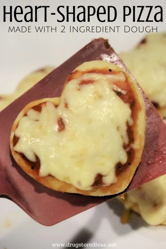 A heart-shaped pizza on a spatula with the words "Heart-Shaped Pizza made from 2 ingredient dough" digitally written on top.