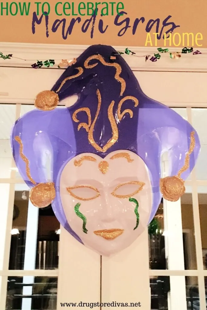 A Mardi Gras mask on a wall with the words "How To Celebrate Mardi Gras At Home" digitally written on top.