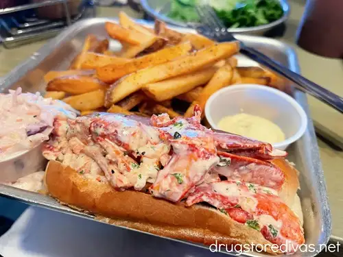 A lobster roll, fries, and coleslaw on a silver tray from Shuckin' Shack Oyster Bar in Leland, NC.