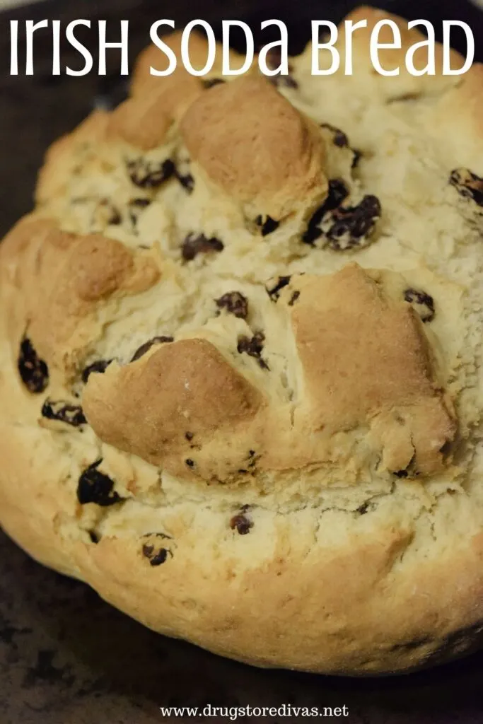 A loaf of soda bread on a pizza stone with the words "Irish Soda Bread" digitally written on top.