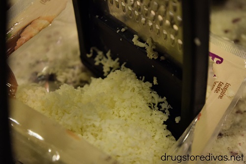 Mozzarella cheese being shredded into a bowl.