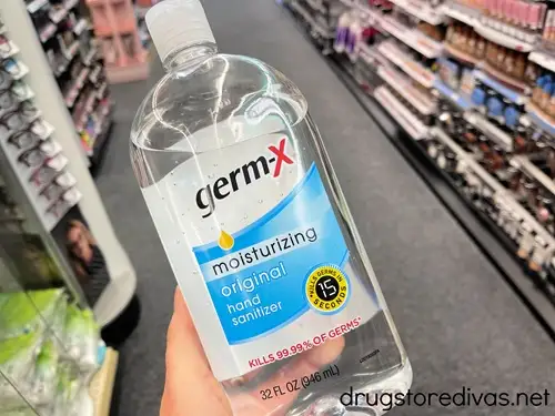 A hand holding a bottle of Germ-X hand sanitizer.