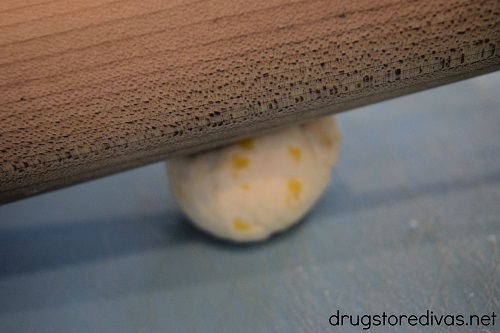 A rolling pin on top of a dough ball.
