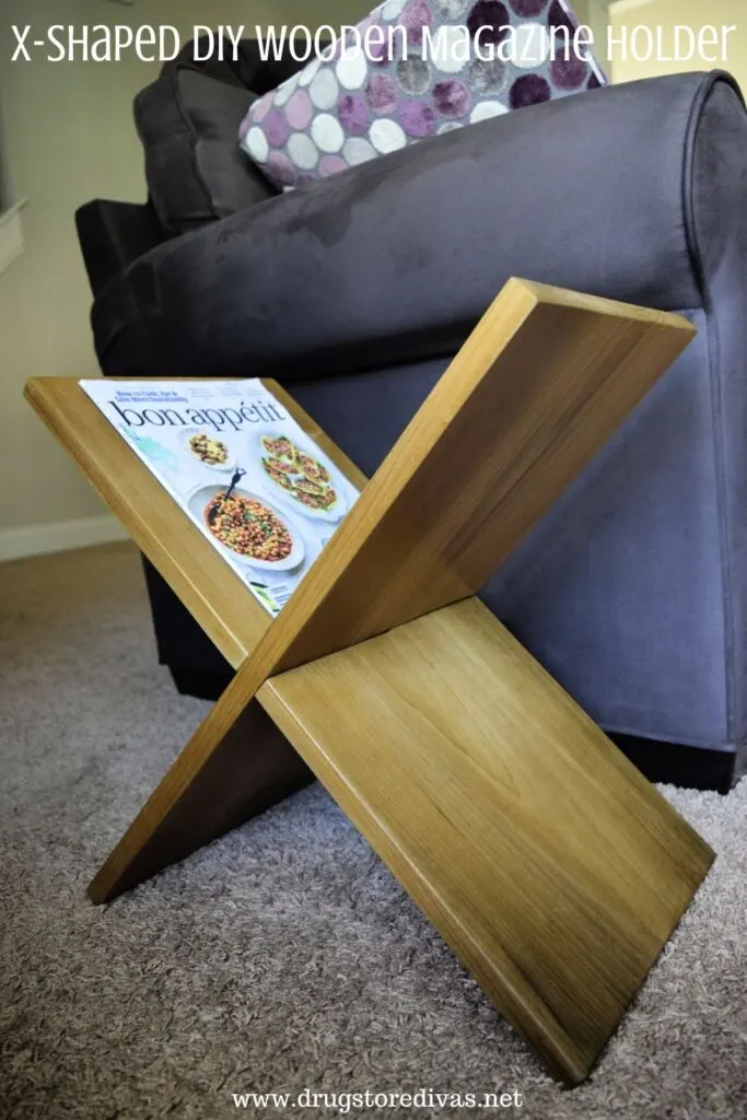 Wooden magazine rack next to a couch with the words "X-Shaped DIY Wooden Magazine Holder" digitally written on top.