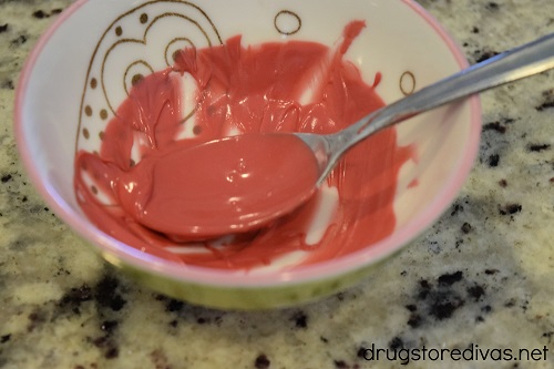 Melted red candy melts in a bowl with a spoon.