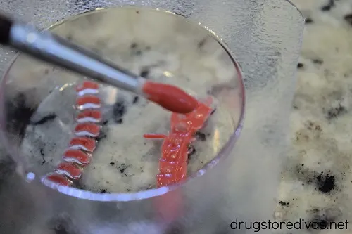 Melted red candy melts on a paint brush being used to paint lines on a baseball chocolate mold.