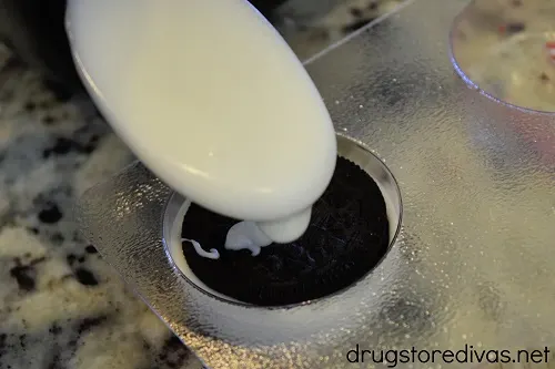 White vanilla almond bark being poured on top of an OREO in an OREO chocolate mold.