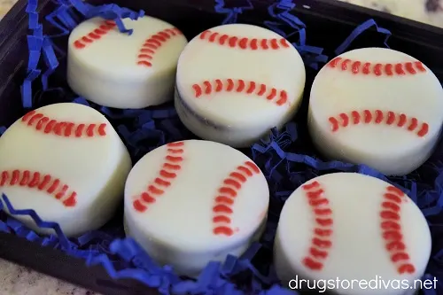 Six chocolate Oreo Baseball cookies on blue paper shred.