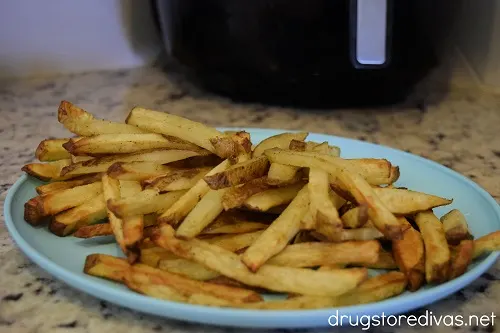 French fries on a plate in front of an air fryer.
