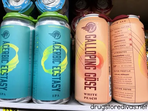 Two light blue cans and two peach cans, both are Broomtail Brewing sour beers, on a shelf at the grocery store.