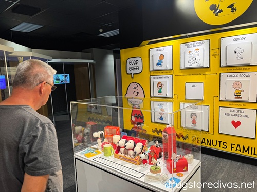A man looking at a Peanuts display featuring Snoopy items at the Hallmark Museum in Kansas City.
