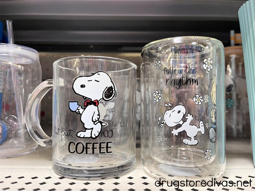 Two Snoopy glasses on a shelf in a store.