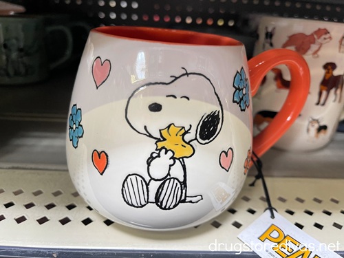 A Snoopy mug on a shelf.