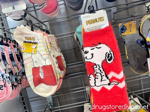 Two pairs of Snoopy socks on pegs in a store.