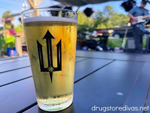 A pint glass of beer with a trident logo on it at Waterman's Brewing Company in Wilmington, NC.