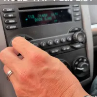 A man changing the car radio dial with the words 