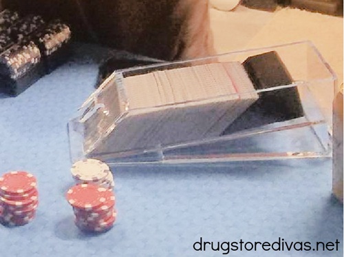 A dealers shoe on a table with poker chips.