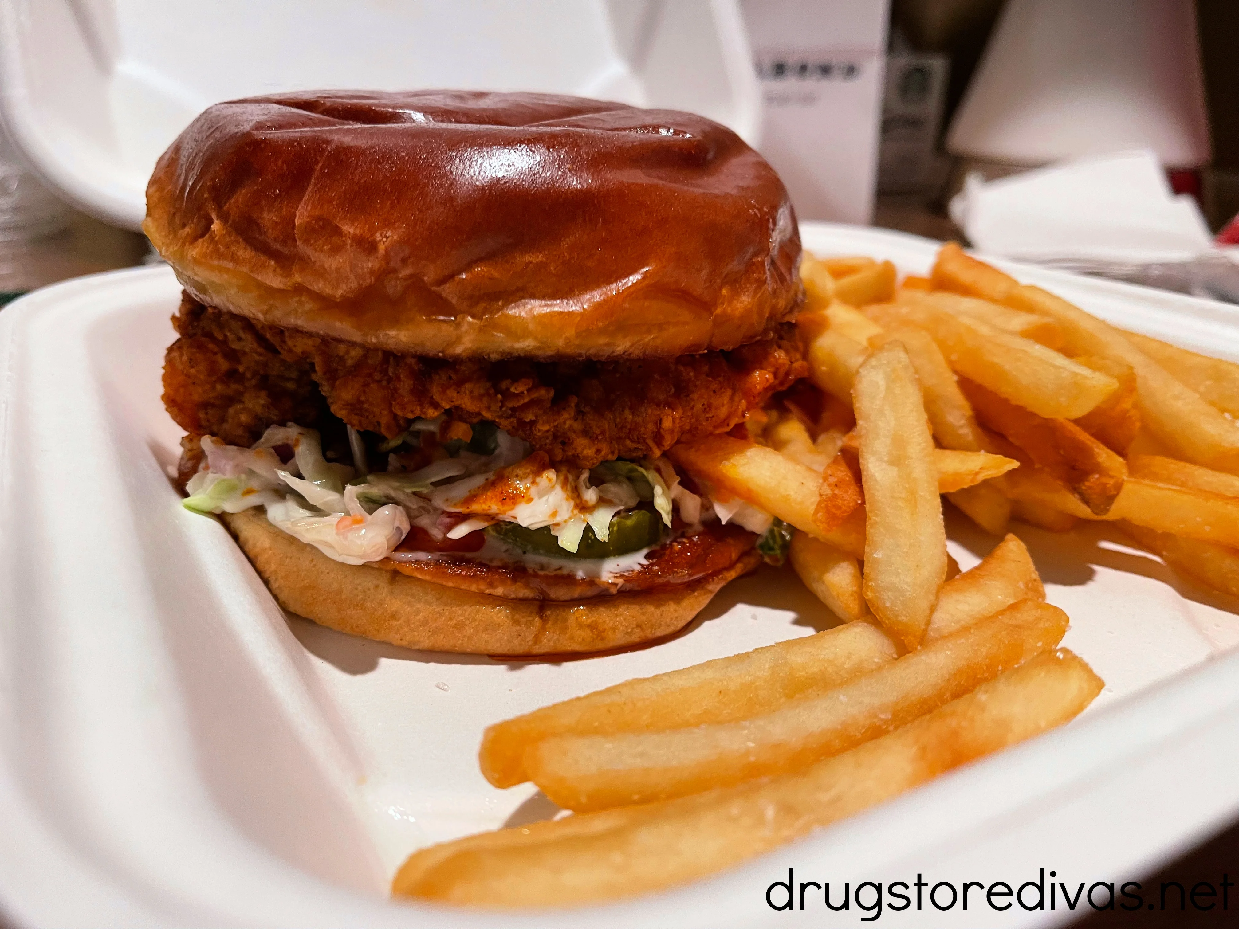 A chicken sandwich and fries in a to go container.