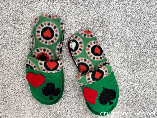 A pair of green slippers with playing card symbols on them.