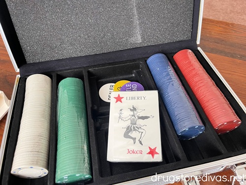 A poker chip set with white, green, blue, and red chips and a deck of cards in the middle.