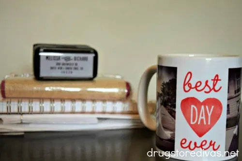 A mug that says best day ever on it with some notebooks in the back.