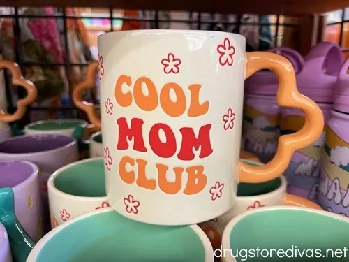 A mug with a half flower handle that says Cool Mom Club.