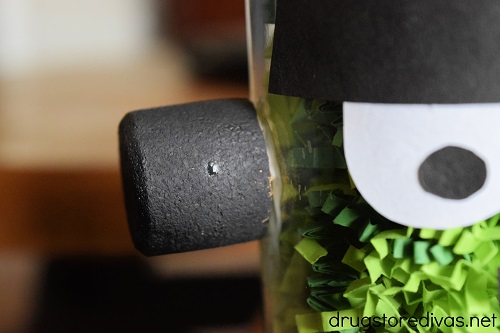 A wine cork, cut in half and painted black, glued onto a mason jar that looks like Frankenstein.