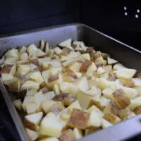 Cubed potatoes in a pan on a charcoal grill with the words 