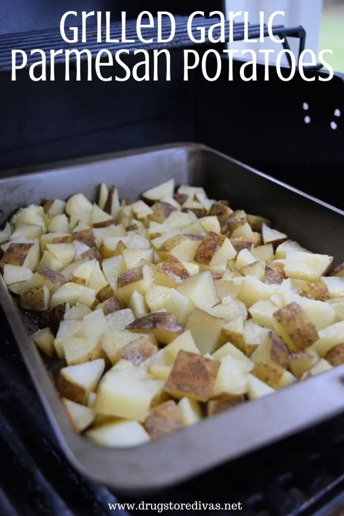 Cubed potatoes in a pan on a charcoal grill with the words "Grilled Garlic Parmesan Potatoes" digitally on top.