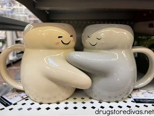 Two mugs shaped like people intertwined like they're hugging.