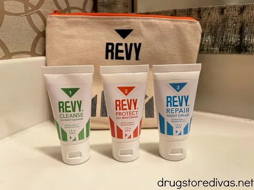 A toiletry bag with three sample sized items in front of it.