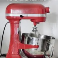 Red stand mixer with metal bowl and the words 